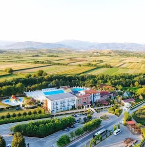 Un hotel con piscina, varias edificaciones y campos aledaños.