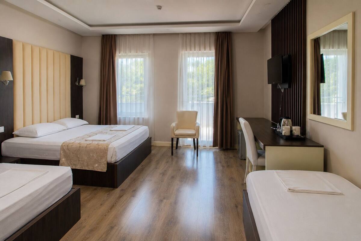 Una habitación de hotel con dos camas, un escritorio, una silla y un televisor.