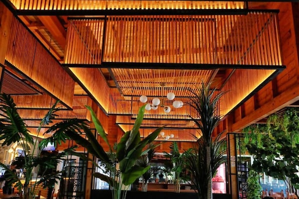 Une piĂšce dotĂ©e dâun plafond en bambou, de grandes fenĂȘtres et de plantes dâintĂ©rieur.
