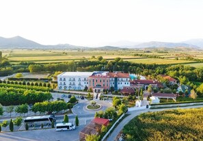An aerial view of a town with a central building, a roundabout, and surrounding greenery.