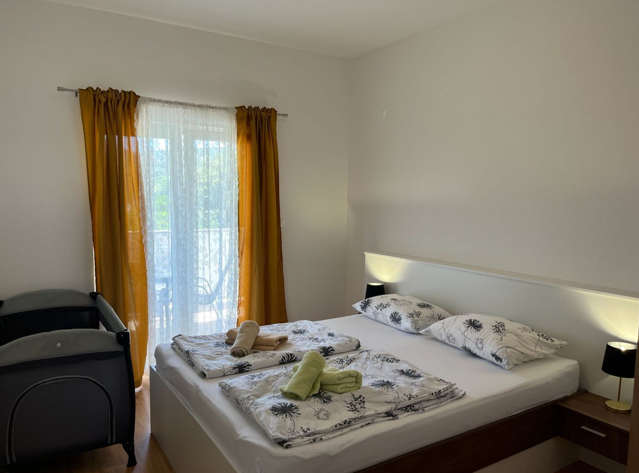 A hotel room with a bed, a chair, a lamp, and a window with curtains.