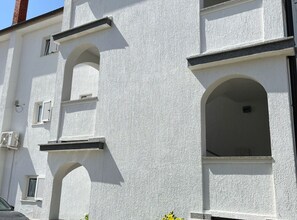 A building with white exterior walls, multiple windows, and a visible chimney. - Apartments Poldan Rab (Lopar)