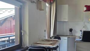 A compact kitchen with a dining table, a refrigerator, and a coffee machine. - Studio on hiking trails and paths.  Ideal for a couple. (Les Gets)