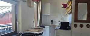 A compact kitchen with a dining table, a refrigerator, and a coffee machine. - Studio on hiking trails and paths.  Ideal for a couple. (Les Gets)
