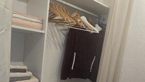 A walk-in closet with shelves, a hanging rack, and a small shelf with a bag and a bottle. - Studio on hiking trails and paths.  Ideal for a couple. (Les Gets)