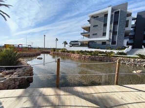 Ein modernes Gebäude mit Pool, Holzterrasse und Palmen.