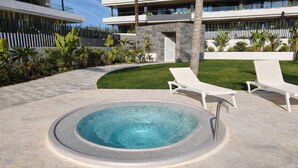 Ein modernes Hotel mit Swimmingpool, Liegestühlen und einem gepflegten Garten.