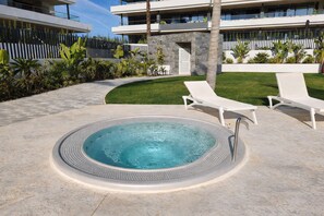 Ein modernes Hotel mit Swimmingpool, Liegestühlen und einem gepflegten Garten.
