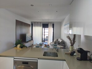 Eine moderne Küche mit Geschirrspüler, ein Essbereich mit einer Couch und Blick durch eine Glastür.
