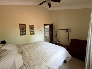 A bedroom with a bed, a wardrobe, a chair, and a door leading to a balcony.