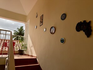 A staircase leading to a balcony with a view of palm trees and a cloudy sky.
