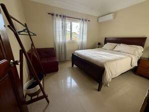 Une chambre à coucher avec un lit, une chaise, une armoire et une fenêtre avec des rideaux.
