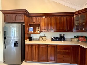 A kitchen with wooden cabinets, a stainless steel refrigerator, a coffee maker, and a box labeled 'Coffee Bar.'