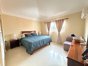A hotel room with a bed, bedside tables, a desk, and a window with curtains.