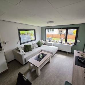 Ein modernes Wohnzimmer mit einer Couch, einem Couchtisch und Blick ins Freie.