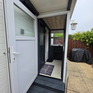 A doorway leading to a covered outdoor area with a wooden deck and a barbecue grill. - Beach Resort Kamperland - 1511 (Kamperland)