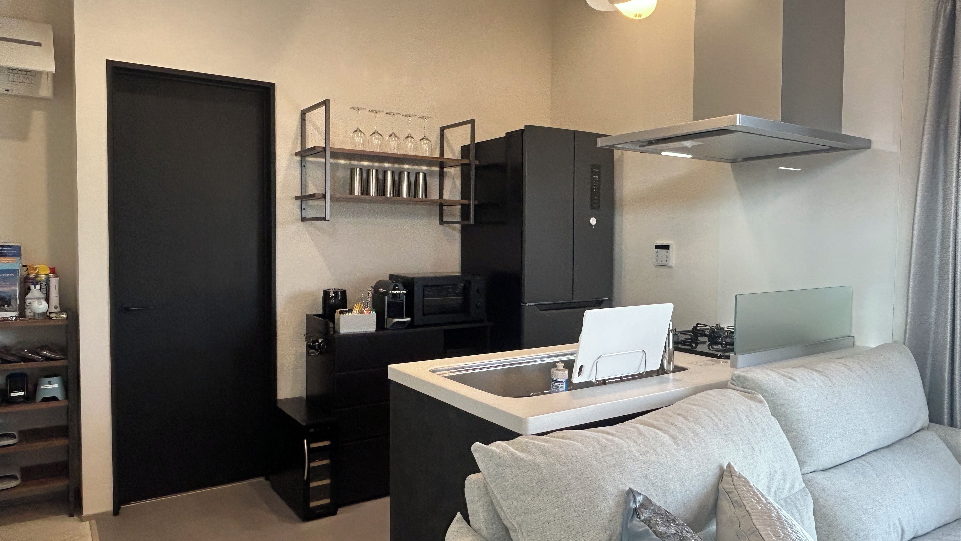Un espacio habitable compacto con kitchenette, un sofá y una mesa de centro.