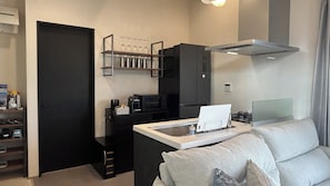 A compact living space with a kitchenette, a sofa, and a coffee table.