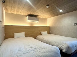 Habitación de hotel con dos camas, techo de madera y aire acondicionado de pared.