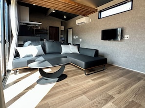 Ein modernes Wohnzimmer mit einem Ecksofa, einem runden Couchtisch und einem flachbildfernseher an der Wand.