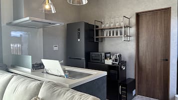 A compact kitchen with a built-in microwave, a coffee machine, and a wine rack.