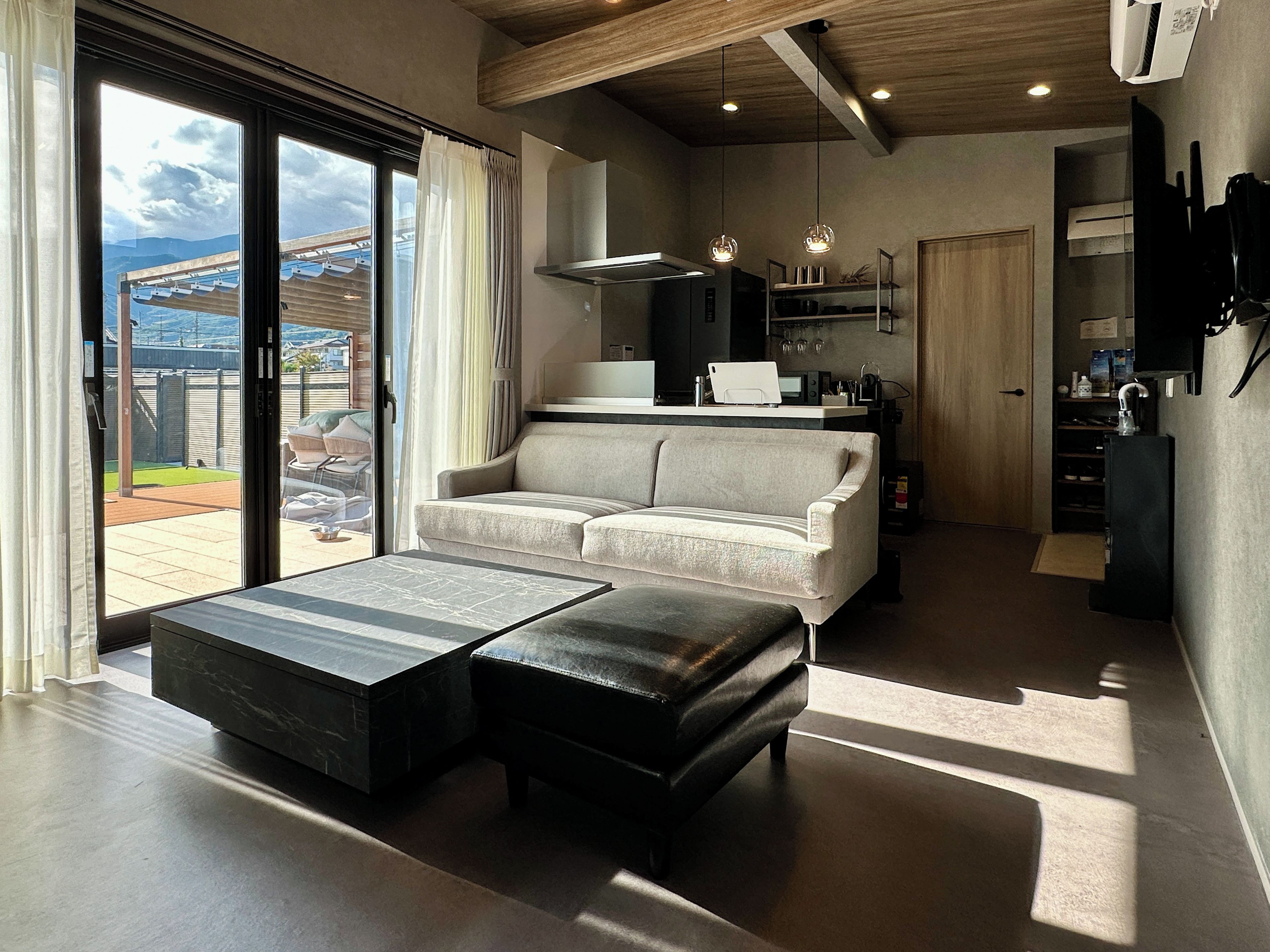 A modern living space with a sofa, a coffee table, and a kitchen area with cabinets and a countertop.