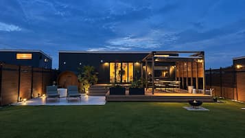 A modern house with a patio, outdoor seating, and a fire pit.