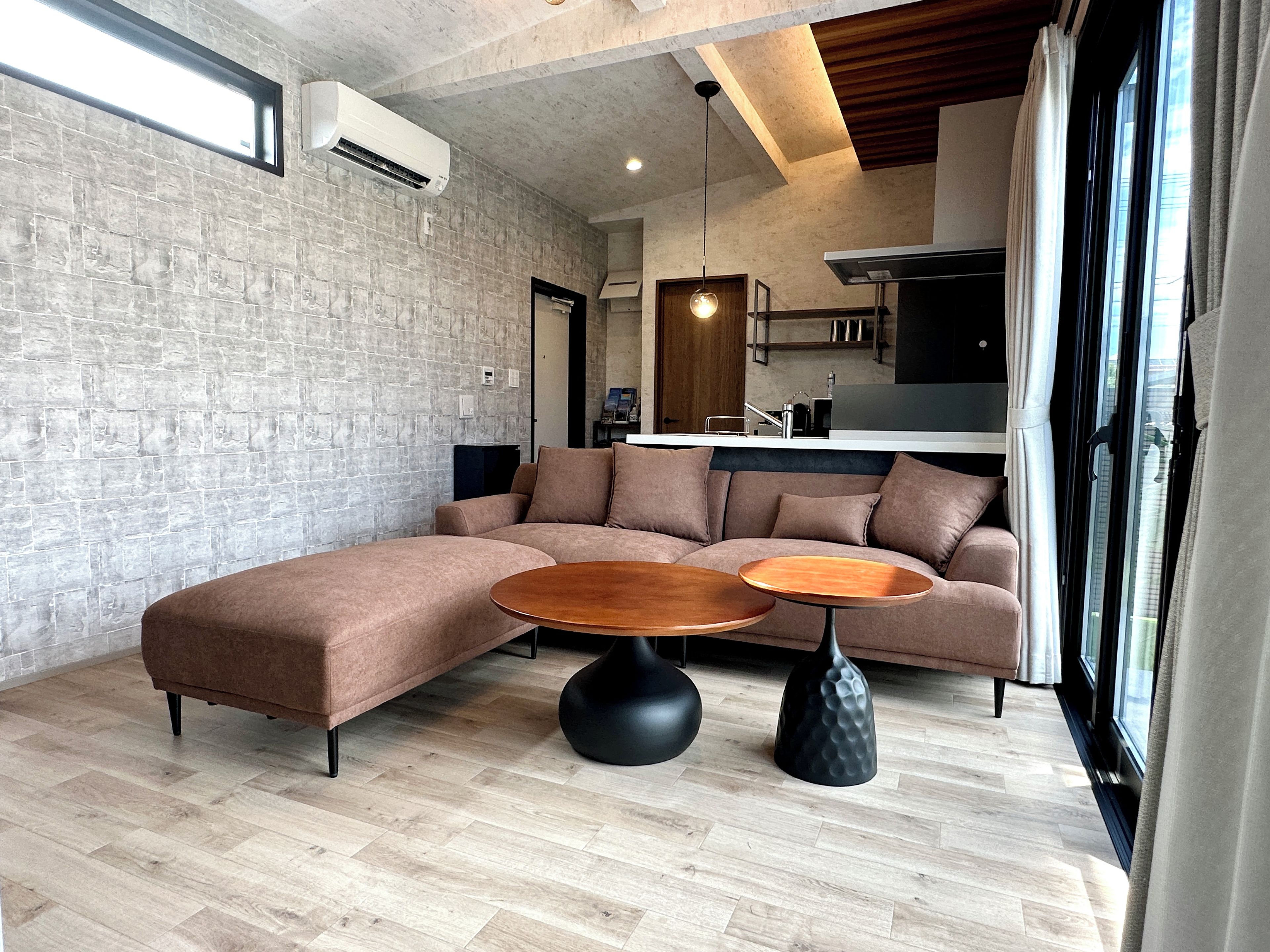 A modern living room with a sectional sofa, two round coffee tables, and a kitchen in the background.