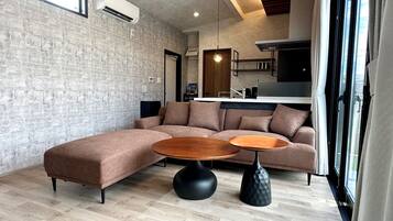 A modern living room with a sectional sofa, two round coffee tables, and a kitchen in the background.
