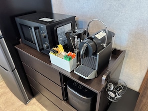 Una cocina equipada con microondas, máquina de espresso y soporte para cápsulas de café.