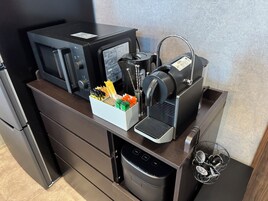 Una cocina equipada con microondas, máquina de espresso y soporte para cápsulas de café.