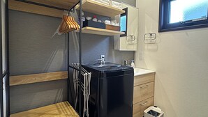 Una kitchenette compacta con un refrigerador negro, estantes de madera y un ventanal.