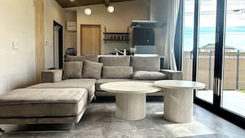 A modern living room with a sectional sofa, two round tables, and a large window with a view.