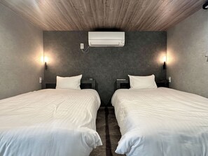 Habitació d'hotel amb dos llits, aire condicionat fixat a la paret i dues parets llum.