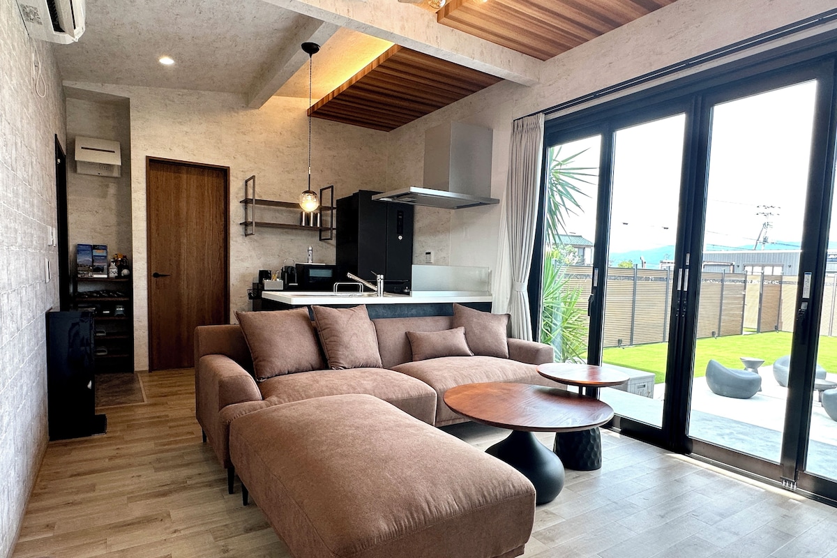 A modern living space with a sectional sofa, a dining table, and a kitchen area.