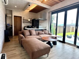 Un espacio habitable moderno con un sofá modular, una mesa de comedor y una zona de cocina.