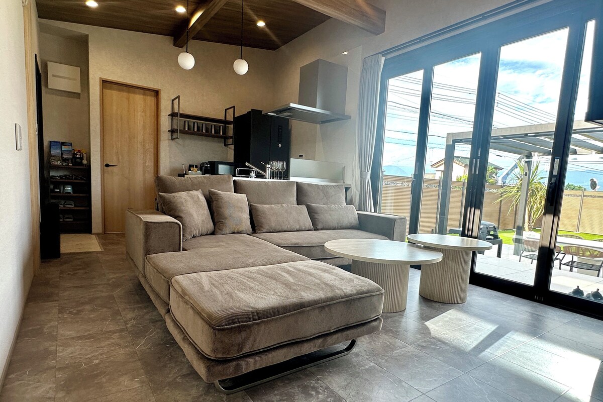 A modern living room with a sectional sofa, a dining table, and a kitchen area.