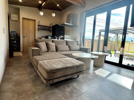 A modern living room with a sectional sofa, a dining table, and a kitchen area.
