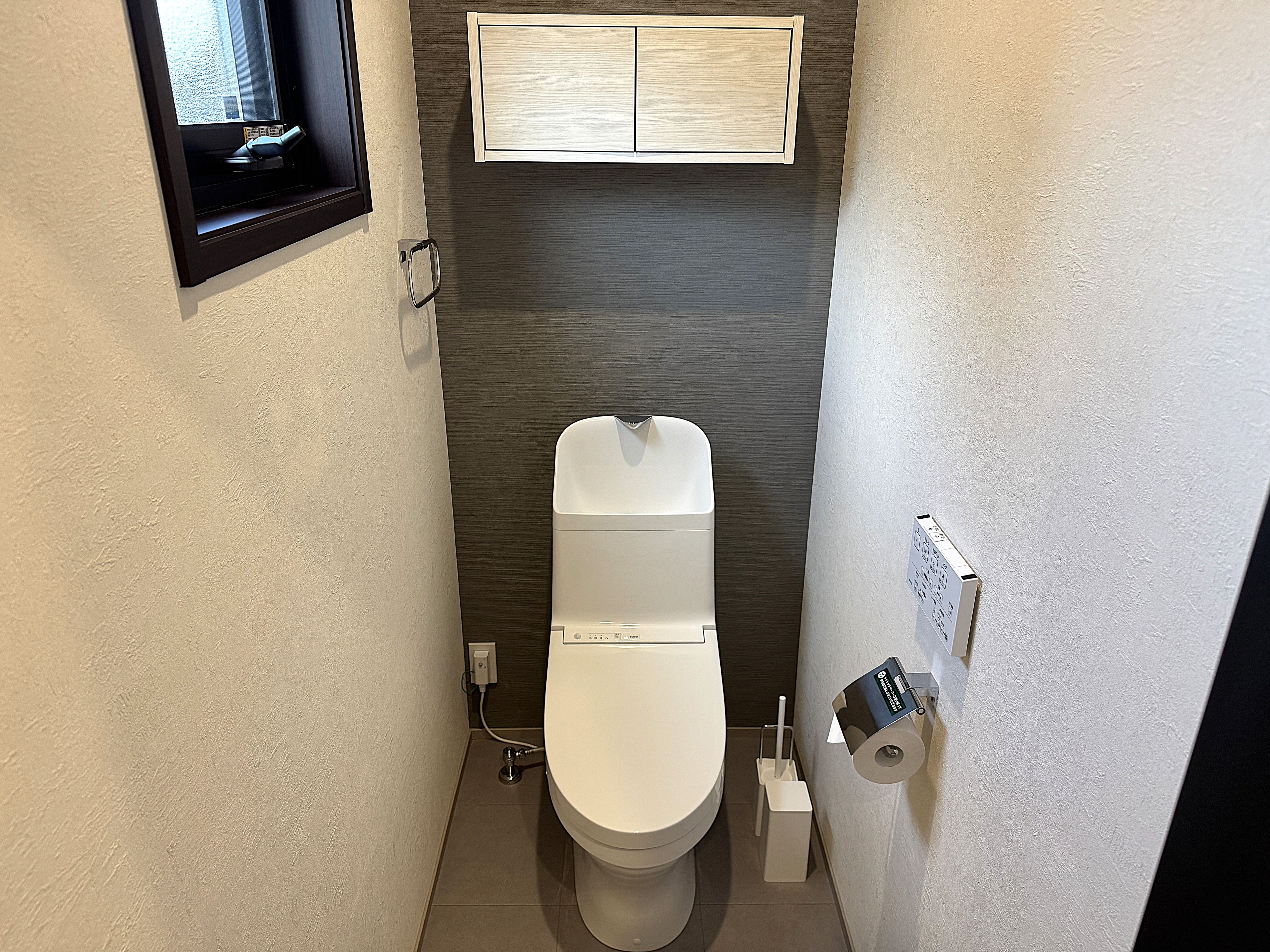 A compact bathroom with a toilet, a hand dryer, and a paper towel dispenser.