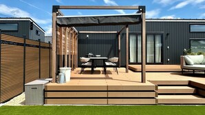 Un patio con mesa y sillas, una parrilla y una zona de estar techada.