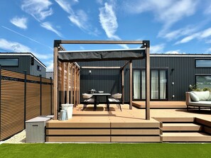 A patio with a table and chairs, a grill, and a covered seating area.