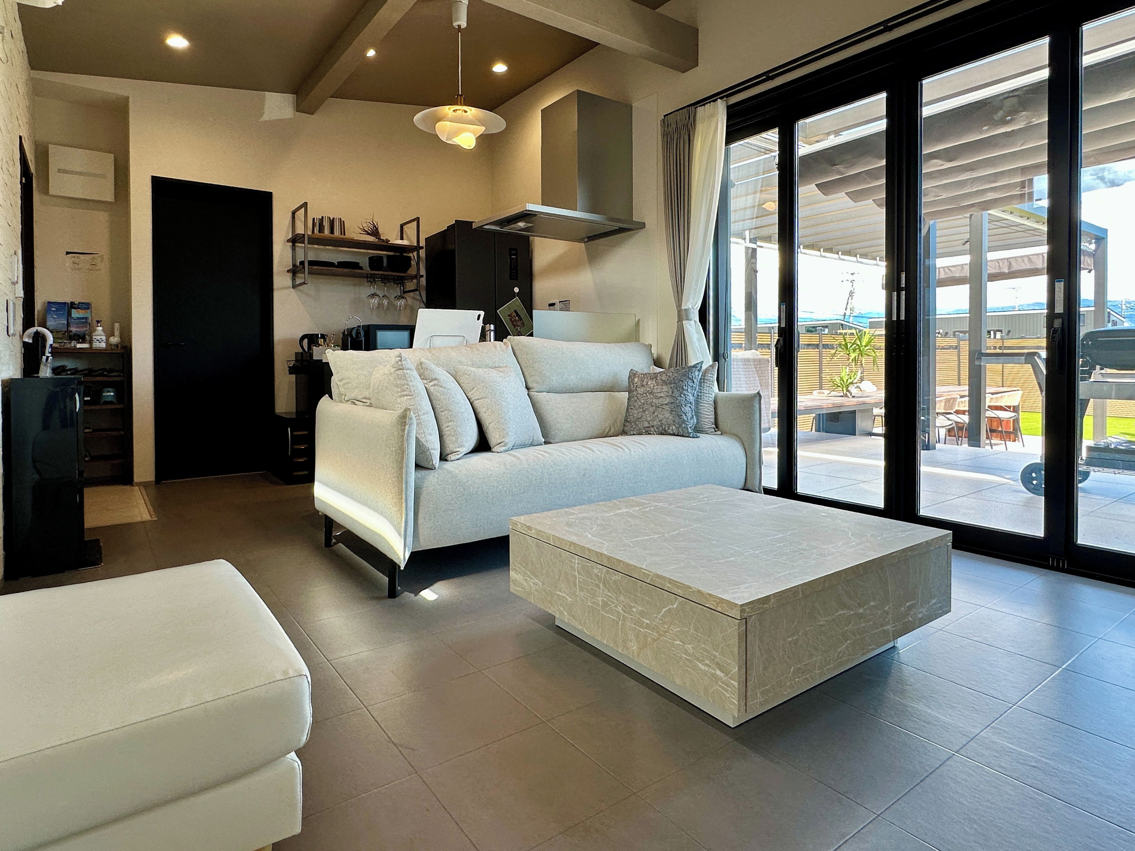A modern living room with a sofa, a coffee table, and a kitchen area with a stove and cabinets.