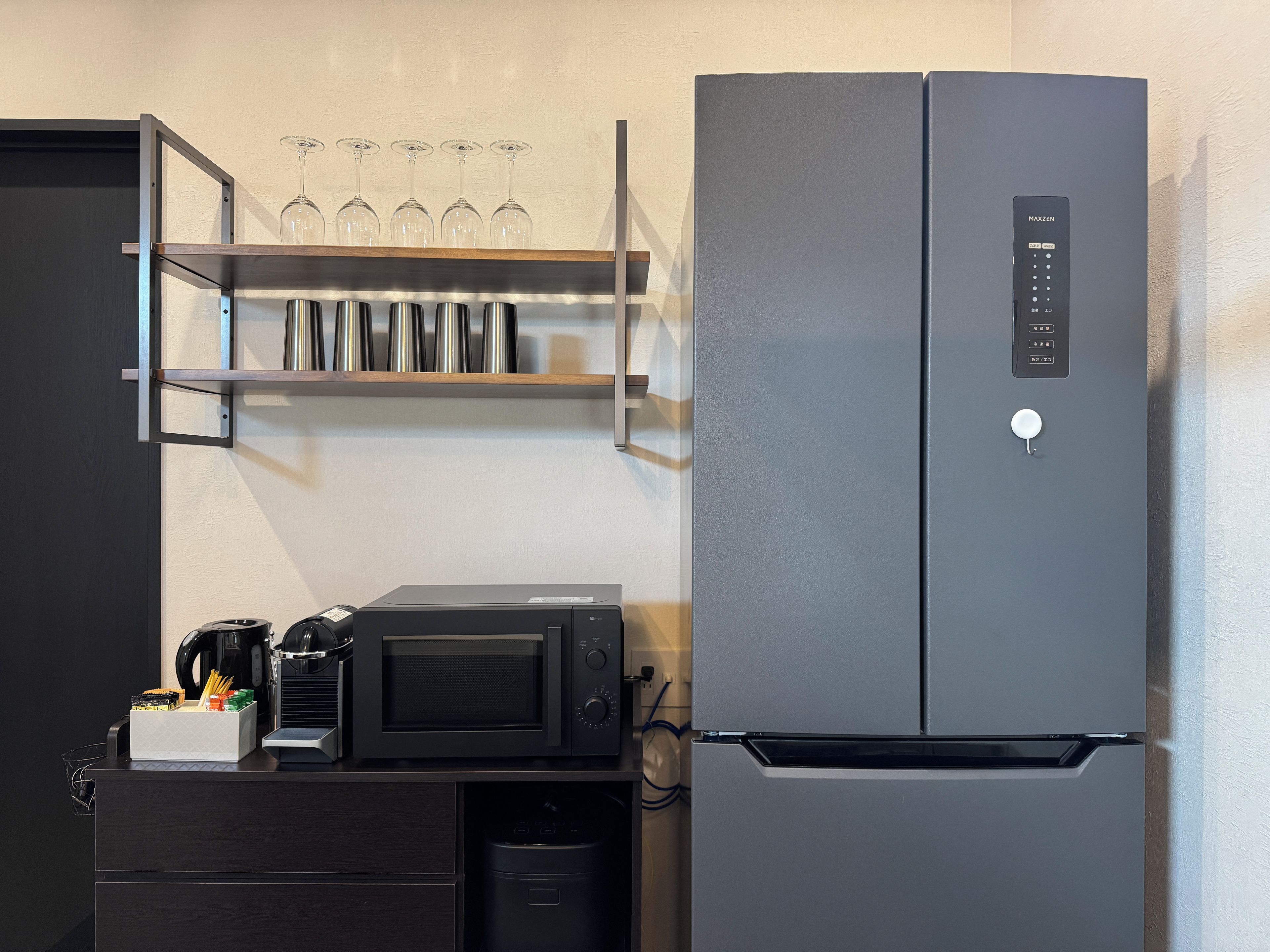 A kitchen with a black refrigerator, a microwave, and a coffee maker on a counter.