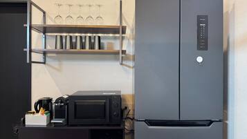 A kitchen with a black refrigerator, a microwave, and a coffee maker on a counter.