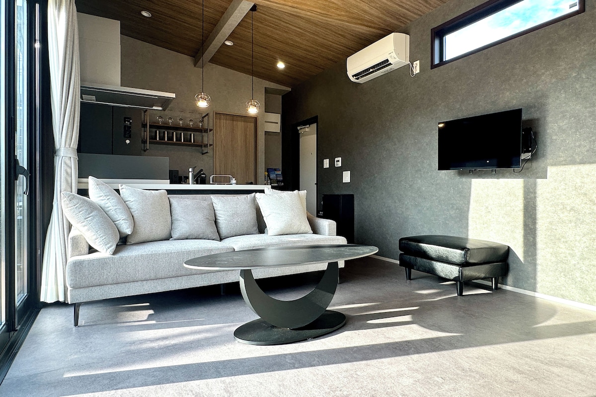 A modern living room with a sofa, a round coffee table, and a television mounted on the wall.
