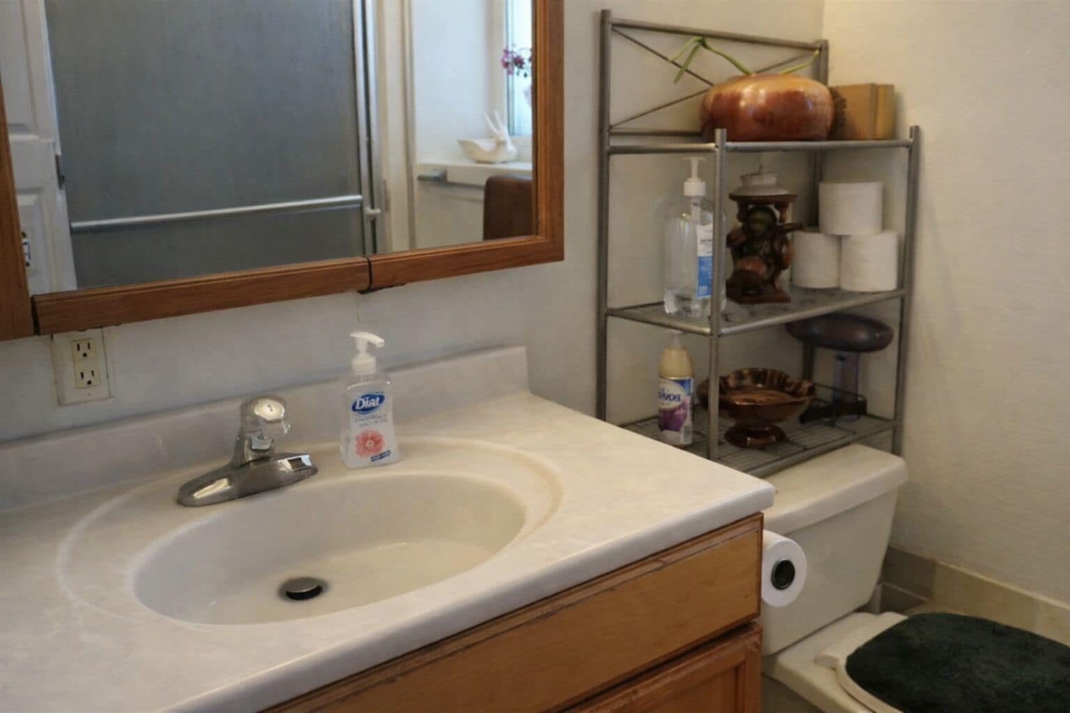A bathroom with a sink, mirror, and shelves with toiletries.. Great room in West Jordan