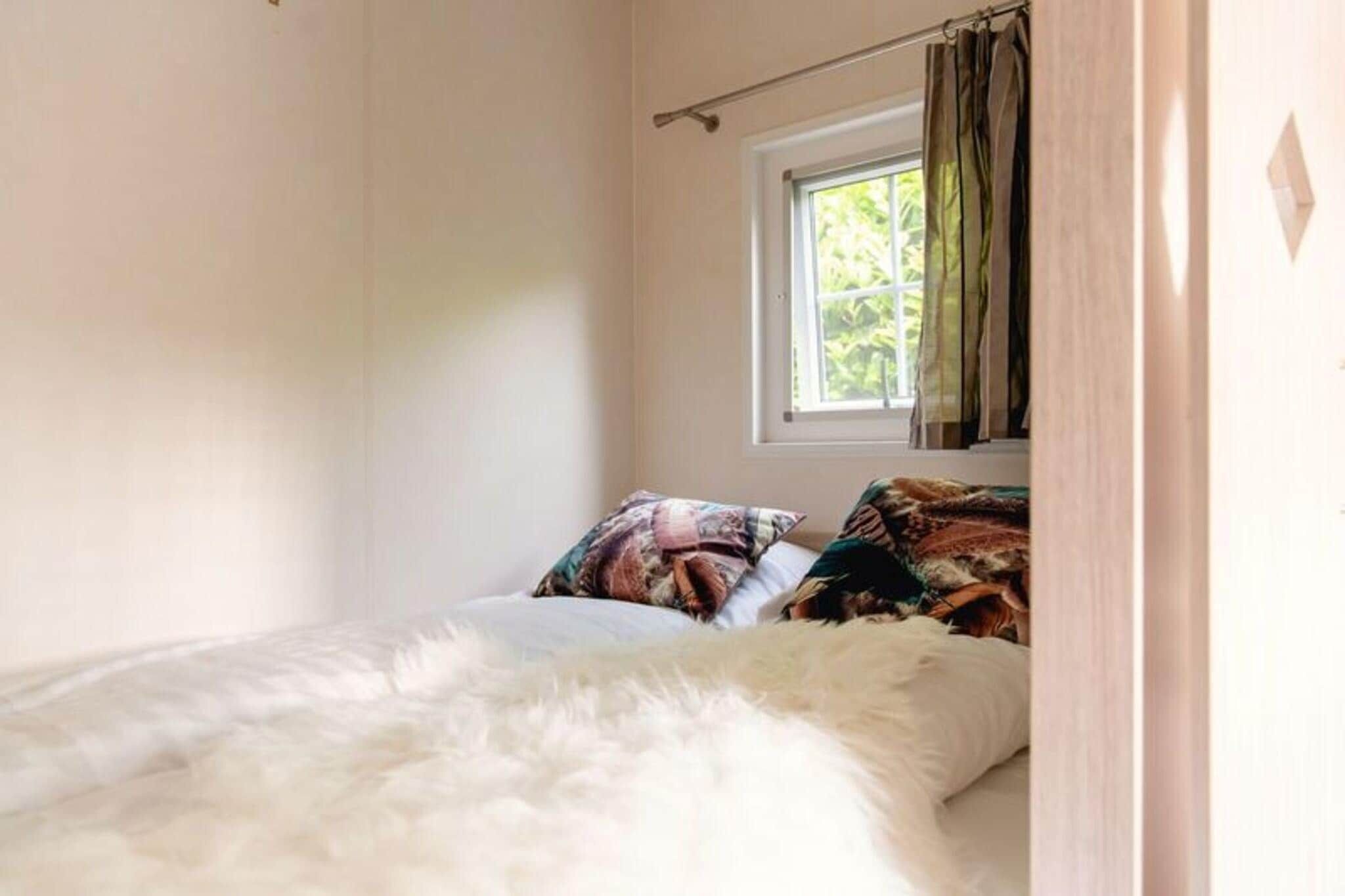Un dormitorio con cama, ventana con cortinas y vistas al verdor exterior.