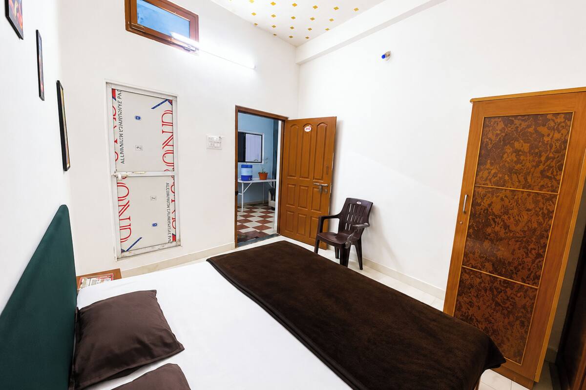 Un dormitorio con cama, una silla, un armario y una puerta que da a un baño.