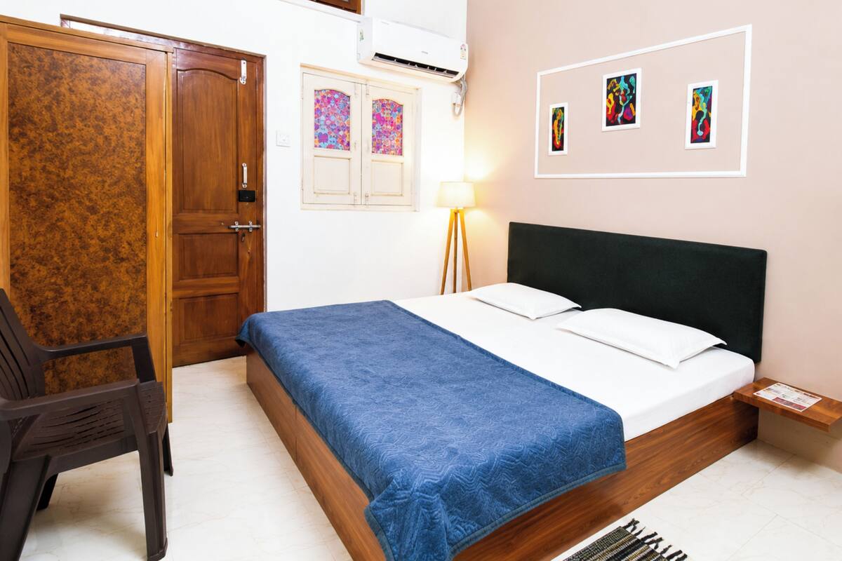 Un dormitorio con cama, escritorio, silla, armario y aire acondicionado instalado en la pared.