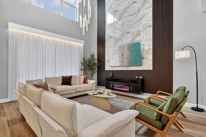 Ein modernes Wohnzimmer mit einer Couch, einem grünen Sessel, einem Kamin und einem großen Fenster.